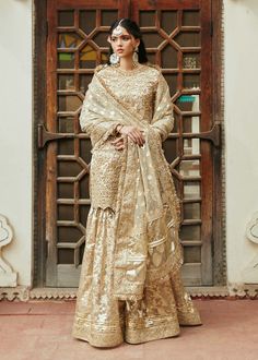 Pakistani Wedding Dress in Kameez Gharara Style is an epitome of beauty. This attire adorned with Sequins, Beads, Motifs, and Tilla is available Online. Raw Silk Sharara With Dabka Work For Wedding, Dabka Work Sharara In Raw Silk For Wedding, Traditional Ceremonies Gold Gown With Dupatta, Gold Gown With Dupatta For Traditional Ceremonies, Intricately Embroidered Raw Silk Sharara For Wedding, Intricate Embroidered Raw Silk Sharara For Wedding, Raw Silk Sharara For Eid Wedding, Intricate Embroidery Raw Silk Sharara For Wedding, Wedding Sharara With Dabka Work For Eid