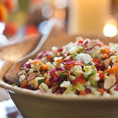 a close up of a bowl of food on a table with candles in the background