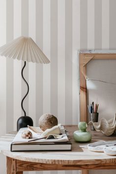 a wooden table topped with books next to a lamp