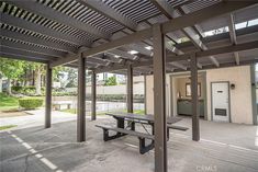 an empty picnic table in the middle of a covered patio with doors to another building