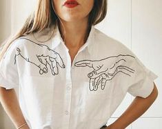 a woman in white shirt with two hands drawn on her chest and one hand pointing at the other