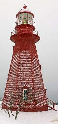 a red light house sitting on top of snow covered ground