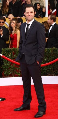 a man in a suit and tie standing on a red carpet