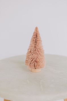 a small pink christmas tree sitting on top of a table