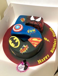 a birthday cake in the shape of a batman and superman symbol on top of it