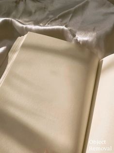 an open book laying on top of a bed next to a white sheet covered pillow