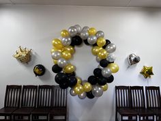 a bunch of balloons are hanging on the wall near some wooden chairs and benches in a room with white walls