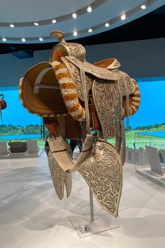 an elaborately designed horse saddle on display in a room with white walls and flooring