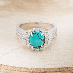 a turquoise stone surrounded by white diamonds on a wooden surface