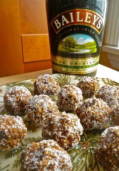 a bottle of bailey's irish whiskey next to some chocolate covered donuts on a plate