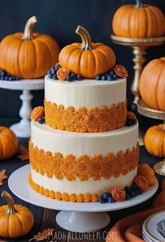 a three tiered cake decorated with blueberries and pumpkins is on a table