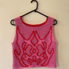 a pink crocheted top hanging on a wall