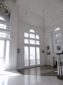 an empty living room with large windows and chandelier