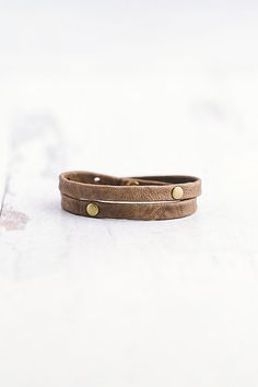 Made for the true warrior, our Double Warrior wrap is a narrow leather bracelet that wraps around the wrist twice and features two flat antique brass rivet accents. **Contents** * Lambskin leather, antique brass hardware * Button clasp closure * Handmade **Care/Import** * Made in the USA **Dimensions** * Adjustable to fit wrist sizes 6.5”-8” | Giving Bracelets Antique Brass Double Warrior Wrap Bracelet at Free People in Grey Gold Leather Wrap Bracelet, Adjustable Brown Metal Wrap Bracelet, Adjustable Brown Leather Bracelet With Brass Hardware, Rustic Brown Adjustable Wrap Bracelet, Brown Leather Hand-wrapped Bracelet For Everyday, Adjustable Vintage Leather Bracelet With Rivets, Vintage Adjustable Leather Bracelet With Rivets, Leather Bracelet Women, Brown Leather Bracelet, Hand Wrapped For Everyday Wear