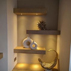 two white vases sitting on top of shelves next to each other in a room