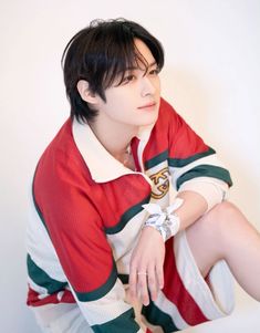 a man sitting on top of a white table wearing a red and green shirt