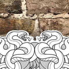 an intricately designed sticker on the side of a brick wall, depicting two snakes