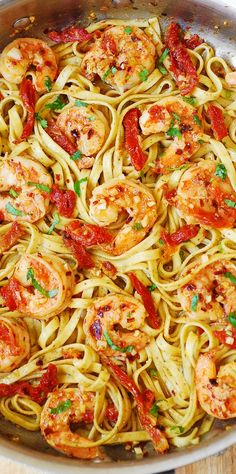 pasta with shrimp and tomato sauce in a pan on a wooden table, ready to be eaten