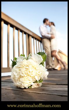 a bouquet of white flowers sitting on top of a wooden floor next to a couple