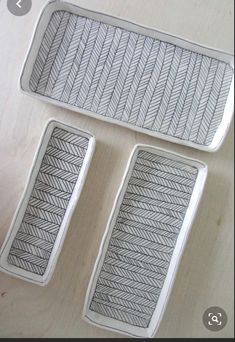 three white trays with black designs on them