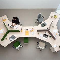 an overhead view of a person working on a laptop at a desk with several chairs