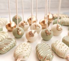 there are many different types of cake pops on the table with gold and white decorations