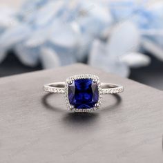 an engagement ring with a cushion cut blue sapphire surrounded by pave diamond halos