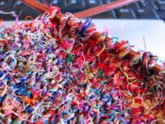 a pile of colorful yarn sitting on top of a laptop computer next to a keyboard