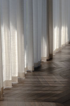 the sun is shining through white curtains in an empty room with wood floors and parquet flooring