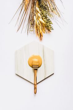 a white wall with a wooden handle next to a palm tree branch and other decorations