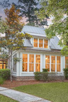 a white house with lots of windows in the front yard and trees on either side