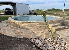 an empty swimming pool surrounded by rocks and gravel