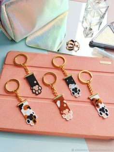 four keychains with different designs on them sitting next to a pink purse and other items