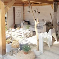 an outdoor living area with white furniture and wood beams on the ceiling, surrounded by potted plants