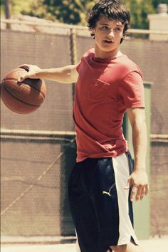 a young man holding a tennis racquet on top of a tennis ball court