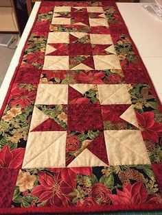 a quilted table runner with poinsettis and flowers on it, sitting on top of a kitchen counter