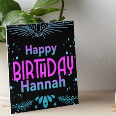 a happy birthday hannah greeting card on a table next to a potted green plant