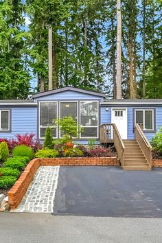 a blue mobile home with landscaping around it and steps leading up to the front door