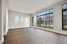 an empty living room with large windows and hard wood flooring on both sides of the wall