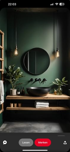 a bathroom with dark green walls and wooden furniture, including a round mirror above the sink