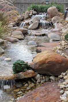 there is a small waterfall in the middle of this rock garden area with rocks and water flowing from it