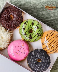 a box filled with different flavored donuts on top of a table