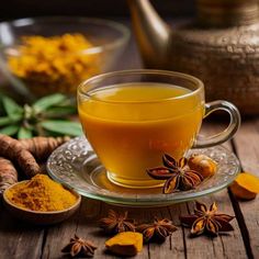 a glass cup filled with yellow liquid next to some spices