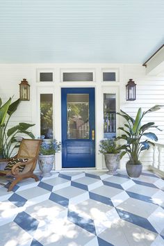 a blue front door with potted plants and a chair on the porch next to it