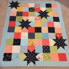 a patchwork quilt is laying on the floor with it's squares and stars