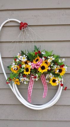 a wreath with sunflowers and daisies hanging on the side of a house