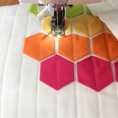 a close up of a sewing machine on top of a piece of fabric with hexagons in the background