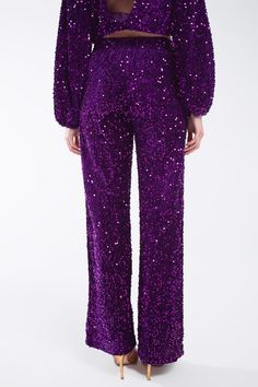 Make a bold statement at the party with our Wide Leg Sequin Pants With Side Pockets in Purple, in a dazzling display of sequins. These super comfy pants combine elegance with comfort, ensuring you shine as the life of the party.  The full-length design and relaxed fit provide a chic and sophisticated look, while the wide leg adds a touch of glamour. The straight silhouette makes these pants versatile, suitable for various occasions and styles.  Featuring elegant side pockets and an elasticated waistband, these pants offer both practicality and comfort. The high waist rise adds a flattering touch, making these sequin pants a stylish choice for your wardrobe.  Crafted from 100% polyester with a polyester lining, these pants offer a luxurious feel against the skin. Whether you choose to pair Disco Style Sequin Bottoms For Party Season, Disco Sequin Bottoms For Party Season, Glamorous Glitter Pants For Party, Embellished Bottoms For Night Out During Party Season, Glitter Bottoms For Evening And Party Season, Party Season Sequined Bottoms, Embellished Bottoms For Evening Parties, Glamorous Holiday Bottoms With Contrast Sequin, Sequin Pants For Night Out And Holidays