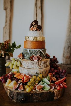 a wedding cake made out of different types of cheese and fruit on a wooden table