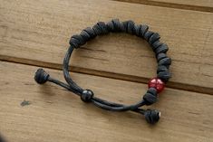 This stunning accessory is designed to help you stay close to our Lord while wearing your faith on your sleeve. Crafted with durable, premium paracord rope in a sleek black/gray color, this adjustable bracelet features 10 knots that represent the 10 Hail Mary prayers. But what truly sets it apart is its unique milky red Our Father bead, reminiscent of the fiery passion and devotion required to vanquish the forces of darkness. Wear this bracelet as a powerful reminder of your commitment to prayer Mary Prayers, Hail Mary Prayer, Knotted Rosary, Paracord Rope, Spiritual Armor, Rosary Bracelet, Our Father, Hail Mary, Adjustable Bracelet